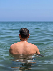 Muscular man standing alone in the middle of the sea