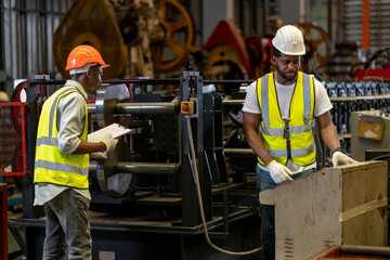 Team of African American industrial worker is checking the setup value of metal sheet roll forming machine by automated monitor while working inside roof factory for safety industry