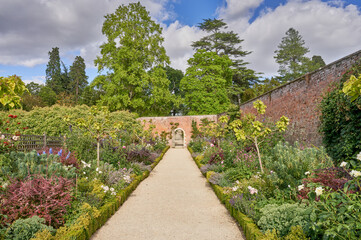 Fototapeta na wymiar Walled garden with gravel path and traditional herbacious perennial planting in summer