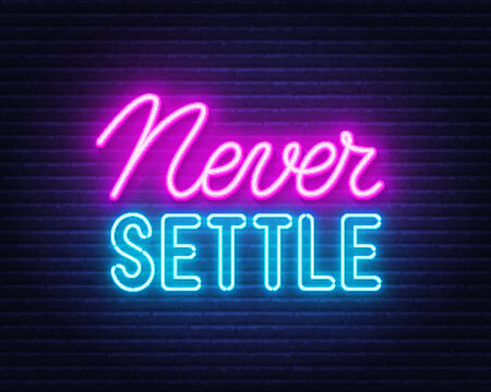 Never Settle l neon quote on a brick wall.