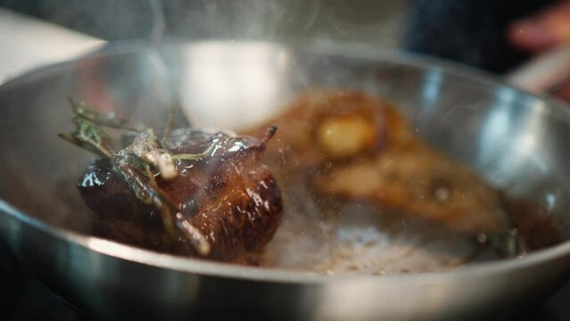 Close-up of filet mignon with thyme being cooked in a frying pan