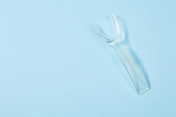 Retractor Dental lip retractor Access to the oral cavity. Wide mouth opening for a dental procedure on a clean blue background