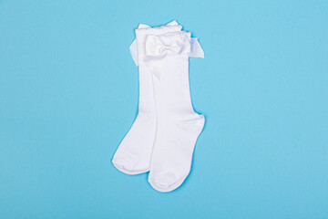 high white children's socks with big bows for festive clothes on a blue background top view