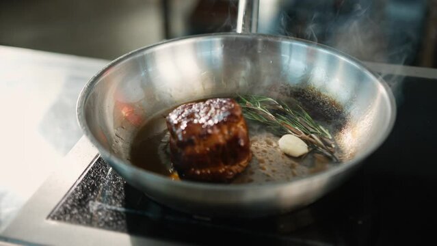 Close-up of filet mignon with thyme being cooked in a frying pan