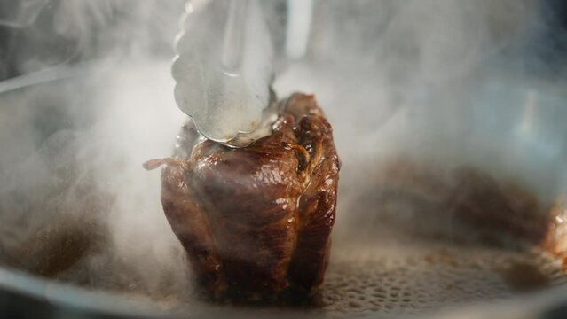 Close-up of a filet mignon being cooked in a frying pan