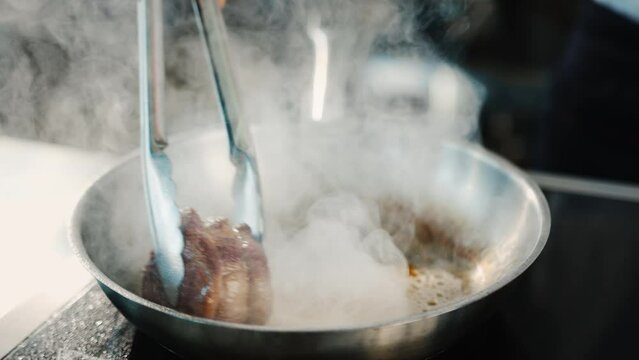 Close-up of a filet mignon being cooked in a frying pan