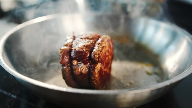 Close-up of a filet mignon being cooked in a frying pan