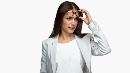 confused businesswoman in grey blazer adjusting eyeglasses isolated on white.