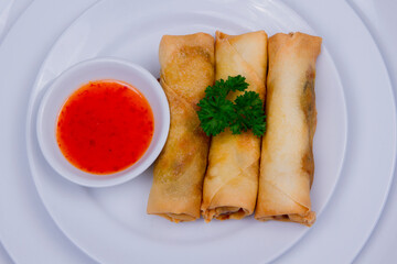 Spring rolls (lumpia) traditional Indonesian food with tomato and chili sauce served on a white plate