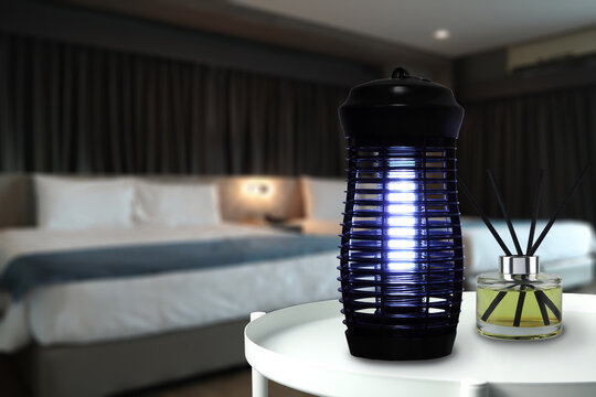 an insects mosquito electric blue light killer lamp is put on the black marble table in the dark bedroom to protect the mosquito during sleeping time