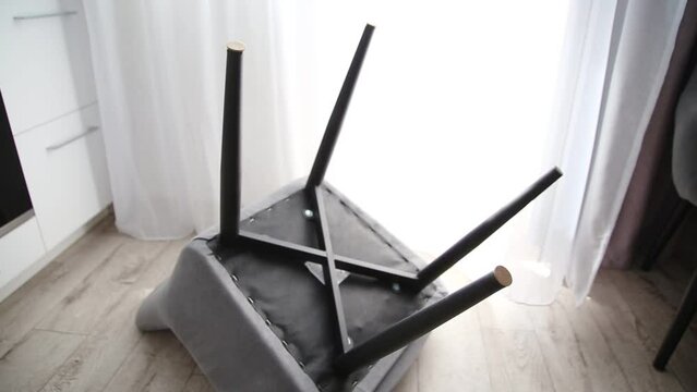 A man glues protective pads on the legs of a chair. Protection against floor scratches and noise
