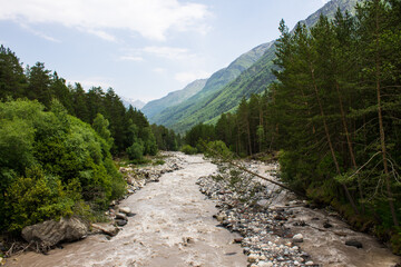 Mountain river Baksan with rocky banks and in a valley from a hill and with green grass in the Elbrus region in the North Caucasus