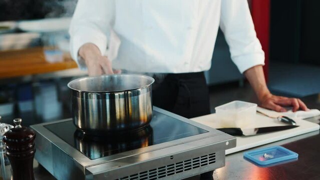 The chef makes sauce in saucepan in a professional restaurant kitchen. The process of food preparation.