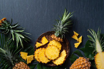 Fresh cut pineapple with tropical leaves on dark blue background.