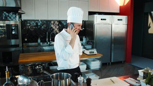The chef is talking on the phone in the kitchen.