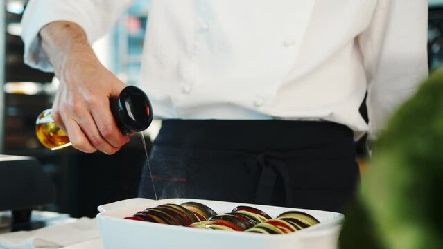 Close-up of a chef preparing to serve ratatouille in bowl. The process of preparing food in a restaurant.