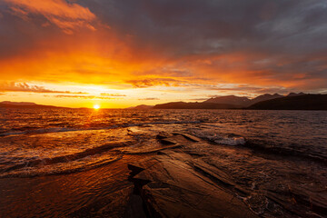 Midnight sun on the sea shore in Norway. Sunset over the coast. Small waves and a strong reflection...