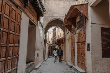People walking through an empty street in the old Medina of Fes
