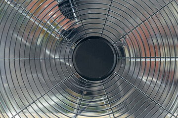 Close up of a big metal fan on the windowsill.