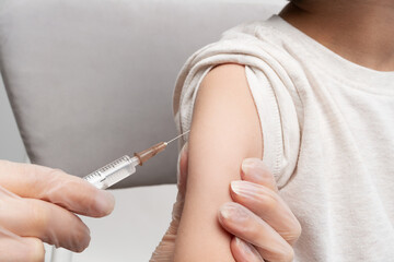 Female doctor injecting vaccination in arm of her little patient. Children vaccination concept. Health care and medicine concept.