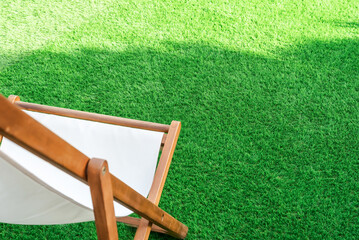 Close-up of a sun lounger on an artificial turf. Green lawn surface ideal for terraces, swimming...