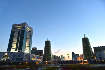 Ministry building in Astana, Kazakhstan and Bajterek tower visible in the distance in background after sunset.