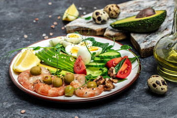 Ketogenic breakfast. Keto low carb shrimps, prawns, quail eggs, fresh salad, tomatoes, cucumbers and avocado on a dark background. keto diet. Top view