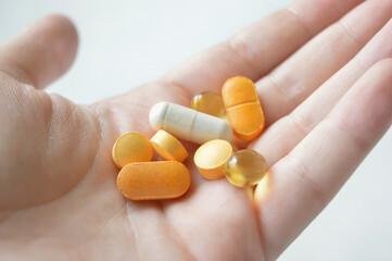 dietary supplements, tablets pills of various colors, held in the hand