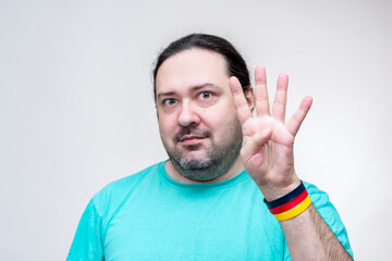 An adult man shows the number four with his fingers. Four outstretched fingers. Bracelet in the colors of the German flag.