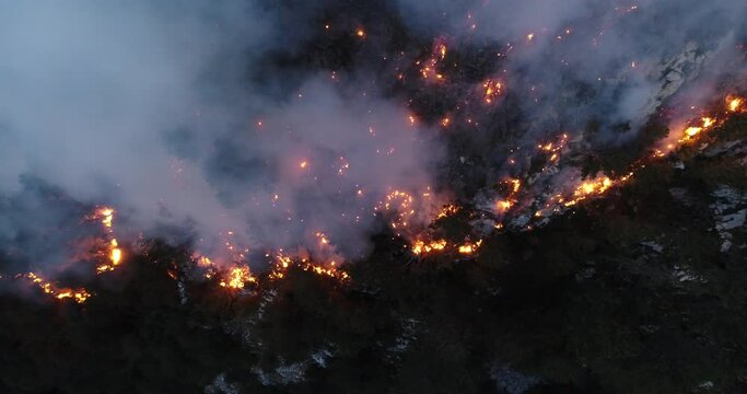 Aerial panoramic view of a forest fire at night, heavy smoke causes air pollution, and fire in full blaze. Natural disaster epic drone cinematic shot.