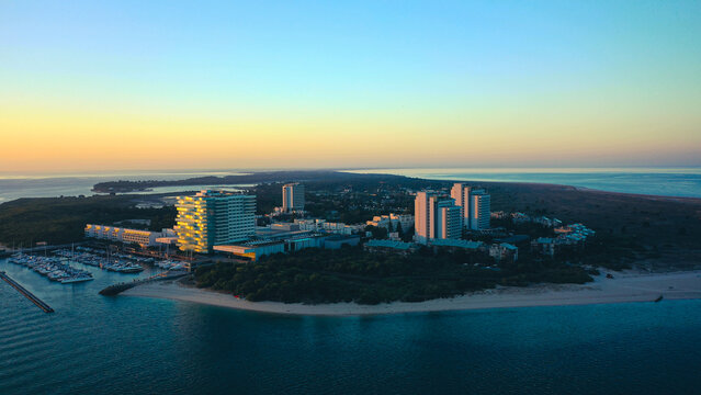 Aerial Bird's eye view of Troia Peninsula on a huge sunrise, near Lisbon. Orange and golden sky in the background