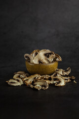 Dry mushrooms in one small plate on a dark background