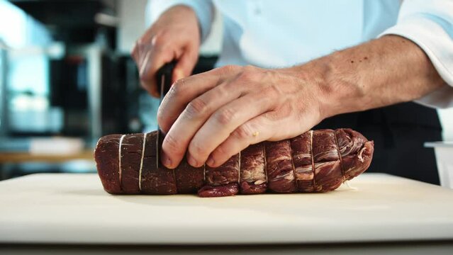 Close-up: The chef cuts the meat of the filet mignon with a knife. The process of preparing food with a restaurant.