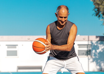 Close-up portrait of Turkish Cypriot senior adult athletic man playing basketball outdoor at summer sunny day