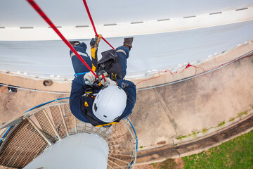 Focus top view male worker down height tank roof rope access safety inspection of thickness storage...