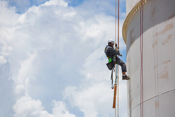 Male worker down height tank roof rope access safety inspection thickness weld of storage tank gas