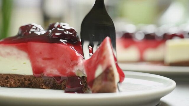 Fork breaks off a piece of no bake cherry cheesecake.
