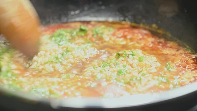 Cooking and stirring the rice in a frying pan.
