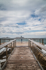 Obraz premium junge Frau bei stürmischen Wetter auf Aussichtsplattform über Meer