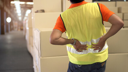 Asian man worker in a warehouse have an accident while carrying a heavy cardboard boxes with...