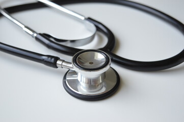 the black stethoscope lying on the white-gray table