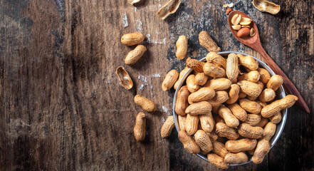 Dried peanuts or nuts on wooden background.Peanut shells on a wooden spoon