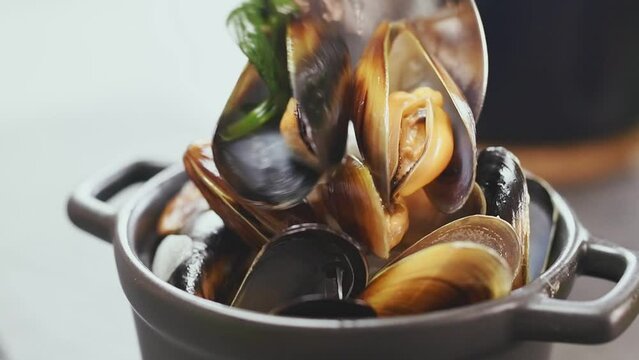 Chef serves delicious freshly prepared mussels on a bowl.
