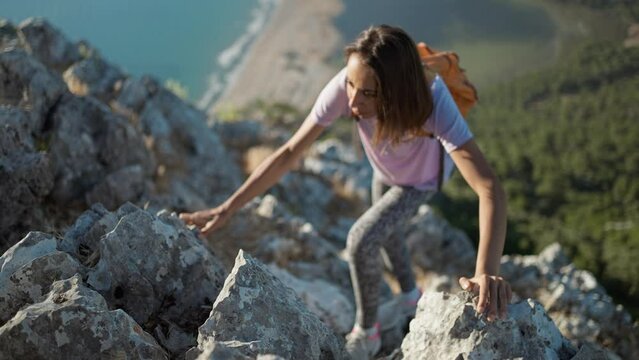 slow motion top view woman hiker rock climber climbs up on cliff on mountain over beautiful sea beach Iztuzu in Turkey, Oludeniz. active lifestyle, healthy leisure, summer outdoors activity.