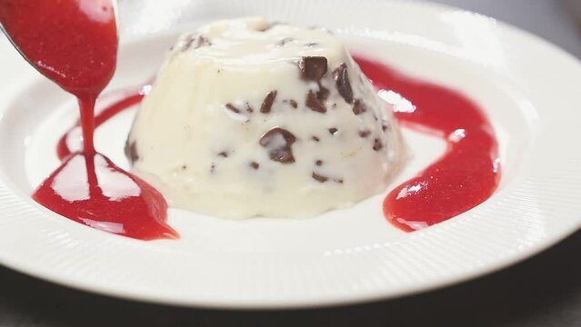 Delicious stracciatella panna cotta with a strawberry sauce.
