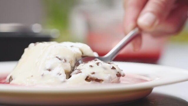 Breaking off a piece of stracciatella panna cotta with a spoon.
