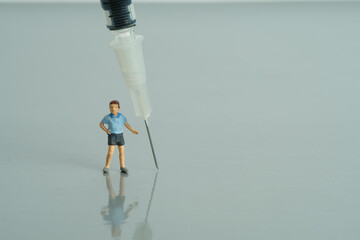 Miniature people toy figure photography. Vaccination for kids concept. A kid boy standing beside...