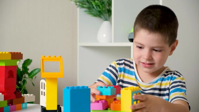 A boy of 5 years old plays as a constructor, builds from multi-colored cubes