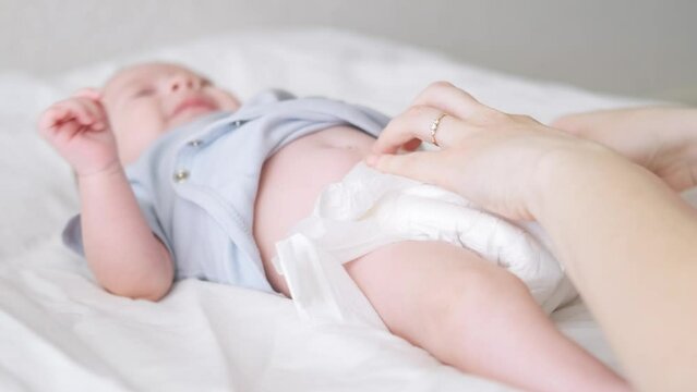 Mother changes diapers to her newborn baby, Little boy on changing table in clean dry nappy, Mom taking care of infant child, motherhood daily routine