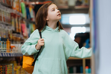 girl with backpack looking away while standing in stationery shop.